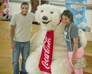 Young male and female pose smiling with the Coca-Cola Polar Bear mascot